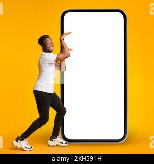 Promo mobile. Drôle de Black Guy faire la danse égyptienne près de Big Blank smartphone Banque D'Images