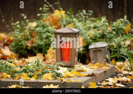 gros plan d'une lanterne sur une tombe recouverte de feuilles d'automne Banque D'Images