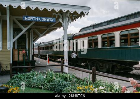 Un train diesel rouge et jaune vintage dans le croisement avec le chef d'orchestre dirigeant les voyageurs à la gare de Conway Scenic Railway. North Conway Banque D'Images