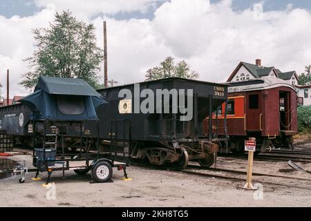 Une tente de camping verte se trouve sur des pilotis au-dessus d'une remorque au milieu de la cour du chemin de fer panoramique de Conway. North Conway, New Hampshire. Image capturée sur un Banque D'Images