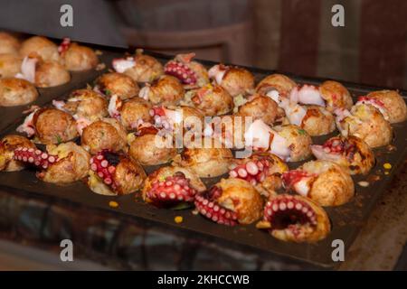 Le takoyaki japonais de la cuisine de rue, ou boulettes de viande de poulpe, cuisant dans un grand lot Banque D'Images