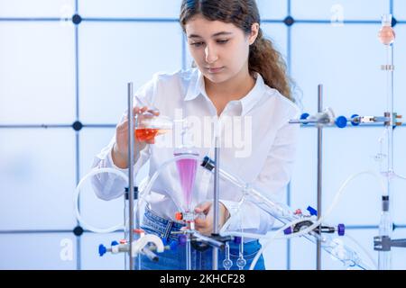 une jeune scientifique adulte conduit une expérience chimique dans un laboratoire de synthèse des hydrocarbures Banque D'Images