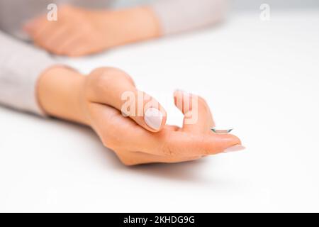 Femme main tenant contact avec les yeux sur la surface blanche. Banque D'Images