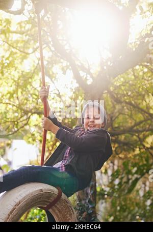 Des journées d'été insouciantes d'une enfance idyllique. Un préadolescent balançant sur une balançoire de pneu dans le jardin. Banque D'Images