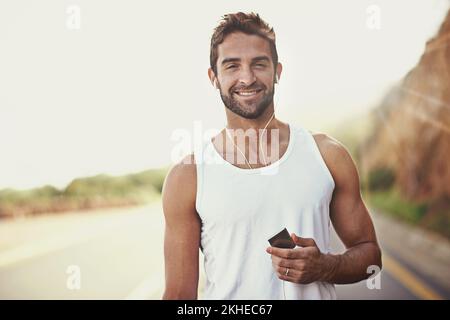 La liste de lecture en cours d'exécution est en attente Portrait d'un jeune homme qui écoute de la musique avec des écouteurs pendant une course. Banque D'Images