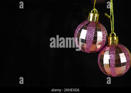 Boules de Noël roses avec paillettes sur fond noir Banque D'Images