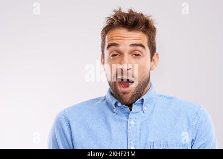 Heure du lit. Photo studio d'un bel homme qui s'ébarde sur fond gris. Banque D'Images