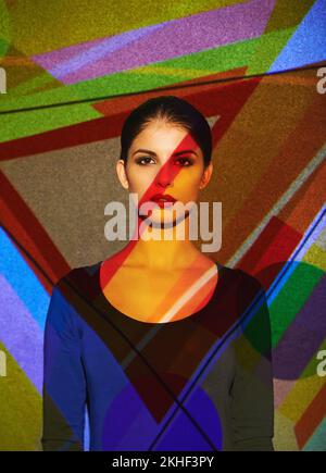 Elle allume une pièce. Un magnifique modèle dans le studio couvert d'une myriade d'éclairage abstrait. Banque D'Images