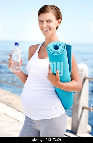 Vous n'êtes qu'à une séance d'entraînement loin d'une grossesse en santé. Portrait d'une belle femme enceinte se préparer pour une séance d'entraînement au bord de la mer. Banque D'Images