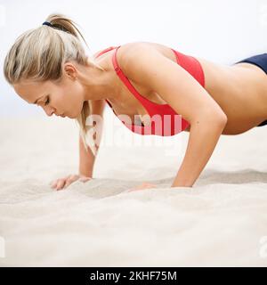 Toujours repousser vos limites. une jeune femme en vêtements de sport faisant des poussettes sur la plage. Banque D'Images