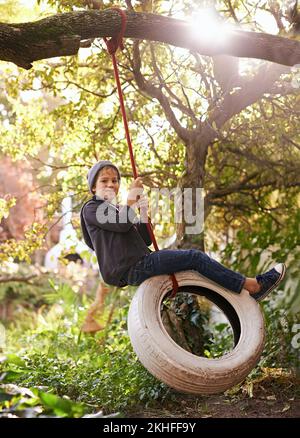 Des journées d'été insouciantes d'une enfance idyllique. Un préadolescent balançant sur une balançoire de pneu dans le jardin. Banque D'Images