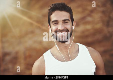 Courir, c'est plus que de l'exercice, c'est un mode de vie. Portrait d'un jeune homme qui écoute de la musique avec des écouteurs pendant une course. Banque D'Images