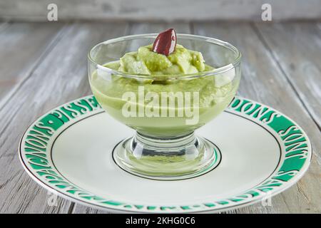 Mousse d'avocat aux olives dans une tasse en verre transparent, sur l'assiette. Banque D'Images