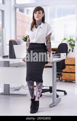Des shes prêts à faire du rock sur la scène de l'entreprise. Une jeune femme d'affaires couverte de tatouage dans son bureau. Banque D'Images