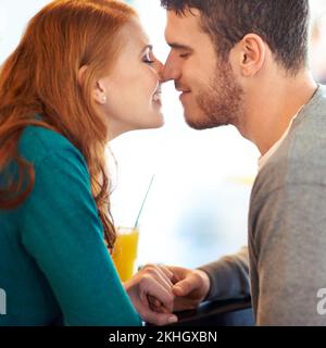 Dans leur petit monde. un jeune couple heureux s'affectueux lorsqu'il est assis dans un café. Banque D'Images