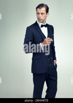 Les vêtements ne font pas l'homme, mais ils peuvent faire l'homme regarder grand. Une photo en studio d'un jeune homme qui fume une cigarette. Banque D'Images