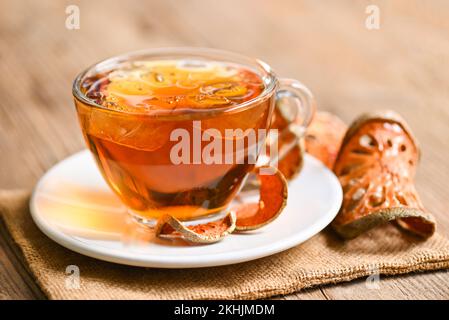 Thé Bael sur verre avec tranches de bael séchées sur fond de bois, jus de Bael - thé sec aux fruits de bael pour la santé - Aegle marmelos Banque D'Images