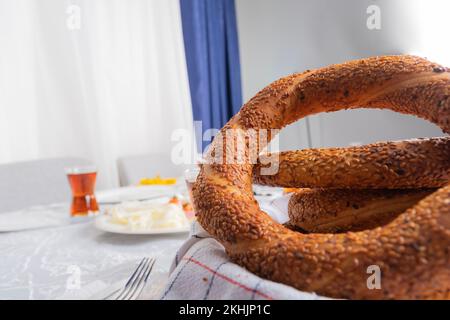 Gros plan sur le bagel turc simit. Petit-déjeuner turc traditionnel, boulangerie, restauration rapide. Verre de thé et de table de mise en place flou d'arrière-plan. Banque D'Images