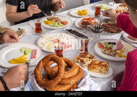 Table de petit déjeuner. Famille ou amis prenant un brunch. Petit déjeuner turc traditionnel. Boire du thé, manger de la saucisse appelée sucuk. Fromage, su borek. Banque D'Images