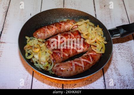 Saucisse cuite dans une poêle avec oignons. Banque D'Images