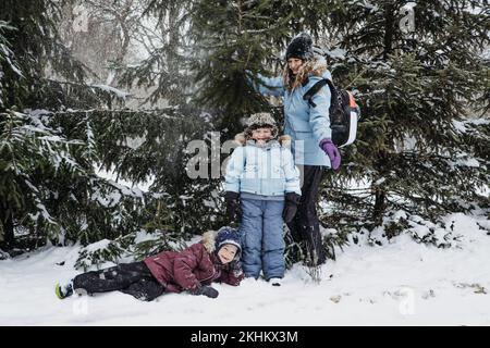 Activités d'hiver en plein air pour la famille, les amis. Famille heureuse, amis, deux femmes, deux enfants et chien, les mères et les fils marchant, s'amusant à l'extérieur Banque D'Images