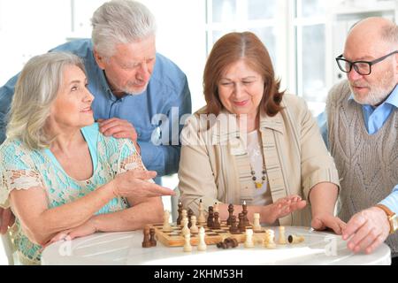 Quatre personnes âgées jouent ensemble une partie d'échecs Banque D'Images