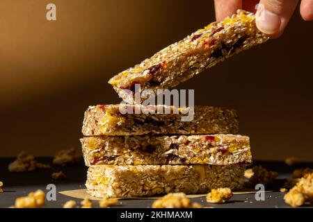 Femme prend le bar énergétique Granola naturel maison. Variété de barres de petit-déjeuner de granola de protéines, avec noix, raisins secs, cerises séchées et chocolat. Nutrition saine alimentation. Collation sans gluten aux céréales Super food Sport Oridge bar Vega dessert concept Banque D'Images