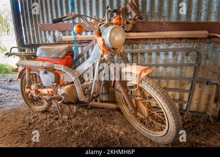 Une Honda CT90 collectant de la poussière dans un hangar situé dans le nord-ouest de la Nouvelle-Galles du Sud, en Australie. Une petite moto intermédiaire de Honda entre 1966 et 1979 Banque D'Images