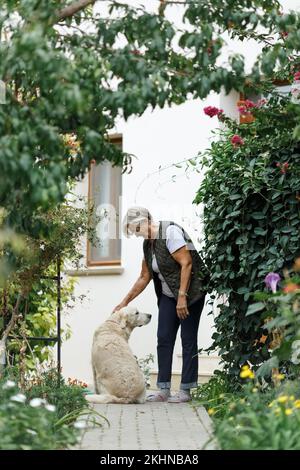 Femme âgée avec chien dans la nature printanière, au repos Banque D'Images