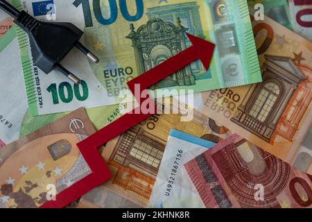 Une fiche électrique et une flèche rouge vers le haut sur les billets en euros - concept de la hausse des prix de l'électricité en Europe Banque D'Images