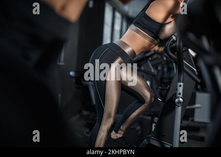 Une fille mince, bodybuilding est engagée dans l'arbitre dans la salle de gym. Concept sportif, combustion de graisse et mode de vie sain. Photo de haute qualité Banque D'Images