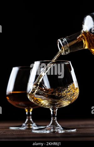 Le Cognac est versé dans un verre à partir d'une bouteille. Banque D'Images