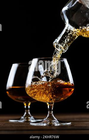 Le Cognac est versé dans un verre à partir d'une bouteille. Banque D'Images