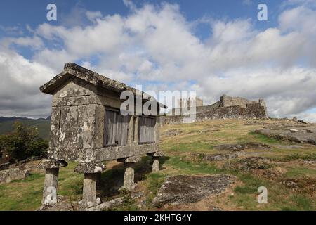 Un vieux grenier (espigueiros) et le château au-dessus du village de Lindoso dans le Parque Nacional da Peneda-Geres, dans le nord du Portugal. Banque D'Images