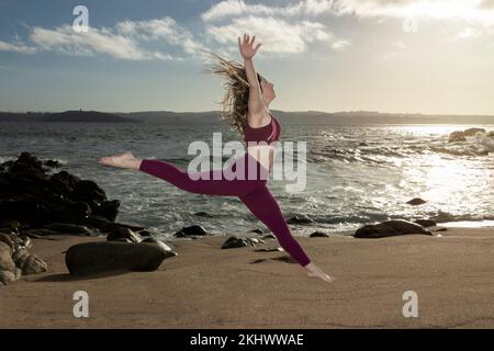 Une femme qui saute dans l'air sur la plage Banque D'Images