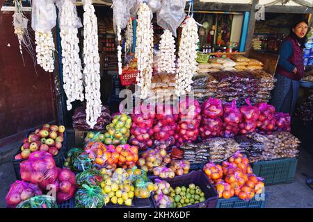 Un stand au bord de la route dans les zones rurales du Bhoutan rempli de pémmons mûrs, de pommes et d'autres produits. Des cordes de Chugo, un fromage dur fait de lait de yak, pendent au-dessus. Banque D'Images