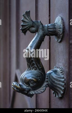 Vue rapprochée de la poignée de porte en bronze vintage en forme de poisson isolée sur une belle ancienne porte en bois marron, Montpellier, France Banque D'Images