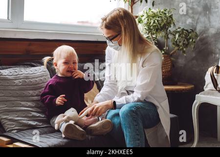 Portrait d'une petite fille triste, assis sur un canapé, pleurant près du médecin des enfants, tenant le lapin en peluche à la maison. Banque D'Images