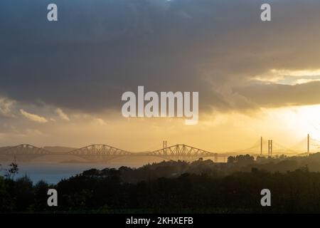 Les trois ponts traversant le Firth of Forth au coucher du soleil depuis la baie de Dalgety, Fife. Banque D'Images