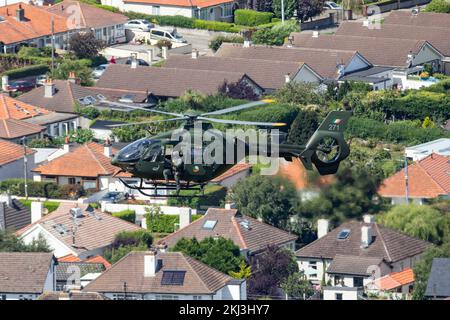 Un hélicoptère vert survolant les bâtiments et une gare ferroviaire pendant le spectacle aérien de Bray Air Display Banque D'Images