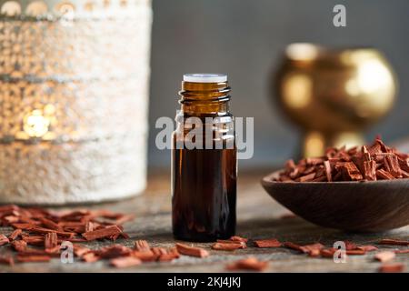 Bouteille sombre d'huile essentielle avec des copeaux de bois de santal rouges et une lampe aromatique Banque D'Images