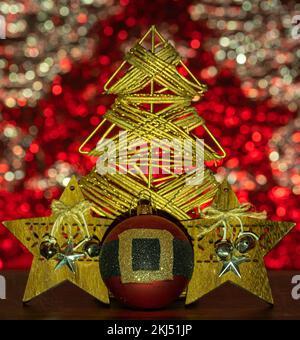 Décoration d'arbre de noël dorée, étoiles et boule rouge devant un mur de bokeh d'el coloré. Banque D'Images