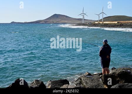 Pêche de l'océan Atlantique avec ligne et pôle de brise-lames avec éoliennes en arrière-plan, village d'El Burrero Gran Canaria Banque D'Images