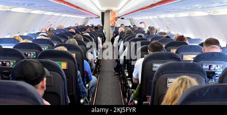 Cabine intérieure d'un avion de ligne commercial avec les passagers à l'arrière de la tête visibles Banque D'Images