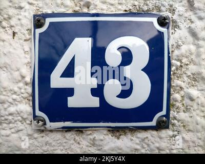 Un numéro de porte carré blanc et bleu foncé de 43 sur un mur en béton Banque D'Images