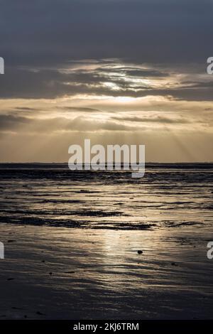 Soleil se brisant à travers les nuages au-dessus du lavage en fin d'après-midi. Vue vers l'ouest depuis la plage de Snettisham, Norfolk. Banque D'Images