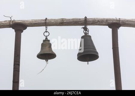 Beffroi en bois simple avec deux cloches suspendues sur fond de brouillard à côté de l'église Saint Giorgi dans la chaîne de montagnes Khvamli en Géorgie. Banque D'Images