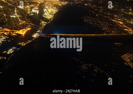 Filmer à partir d'une fenêtre d'avion. Vue imprenable sur la ville nocturne, métropole illuminée de lumières dorées. Bleu foncé ciel nocturne. Abstraction. Voyage, ou Banque D'Images