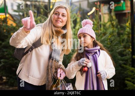 Préteen fille avec la mère sélectionnant arbre de Noël sur la foire extérieure Banque D'Images