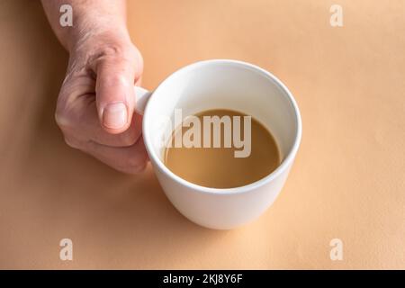 Une femme âgée tient en main le café du matin avec du lait en main. Banque D'Images